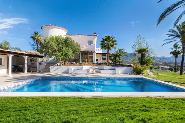 White villa with a crystal blue pool on a sunny day