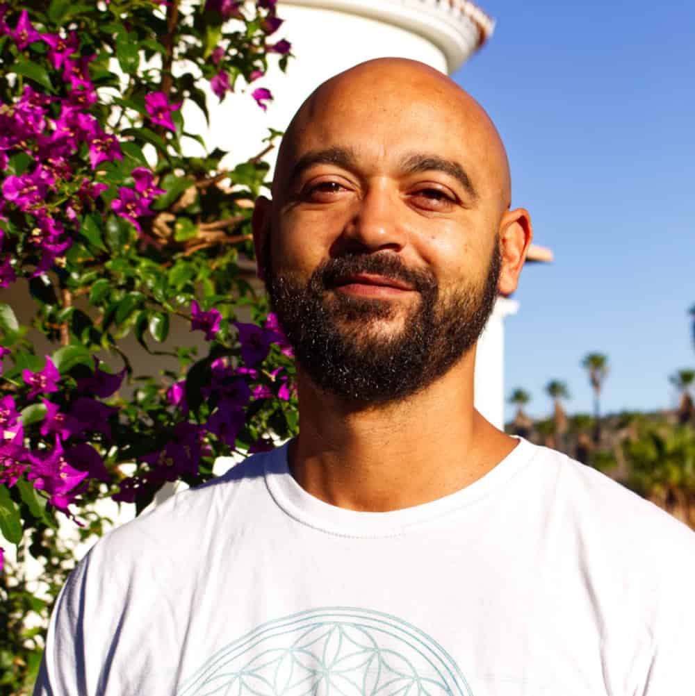 Balled guy with a black beard, wearing a white shirt