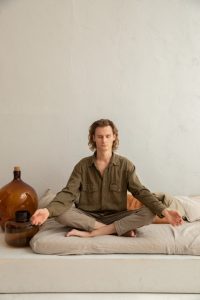 Young blonde guy meditating in white room