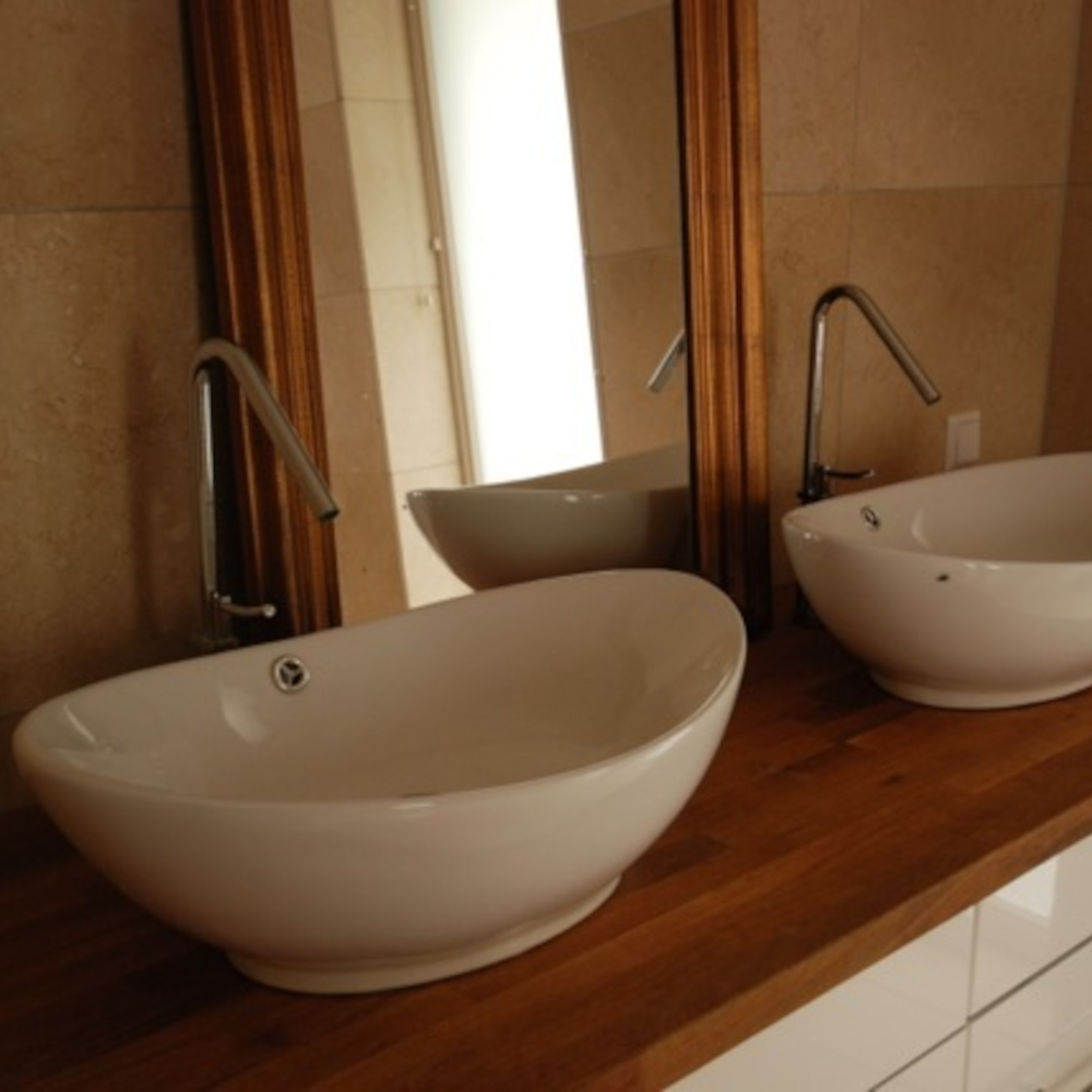 Two modern and white bathroom sinks with a mirror on wood elements