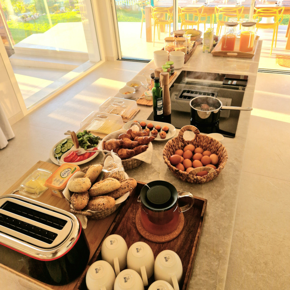 Kitchen table with breakfast buffet, sun is shining into the kitchen