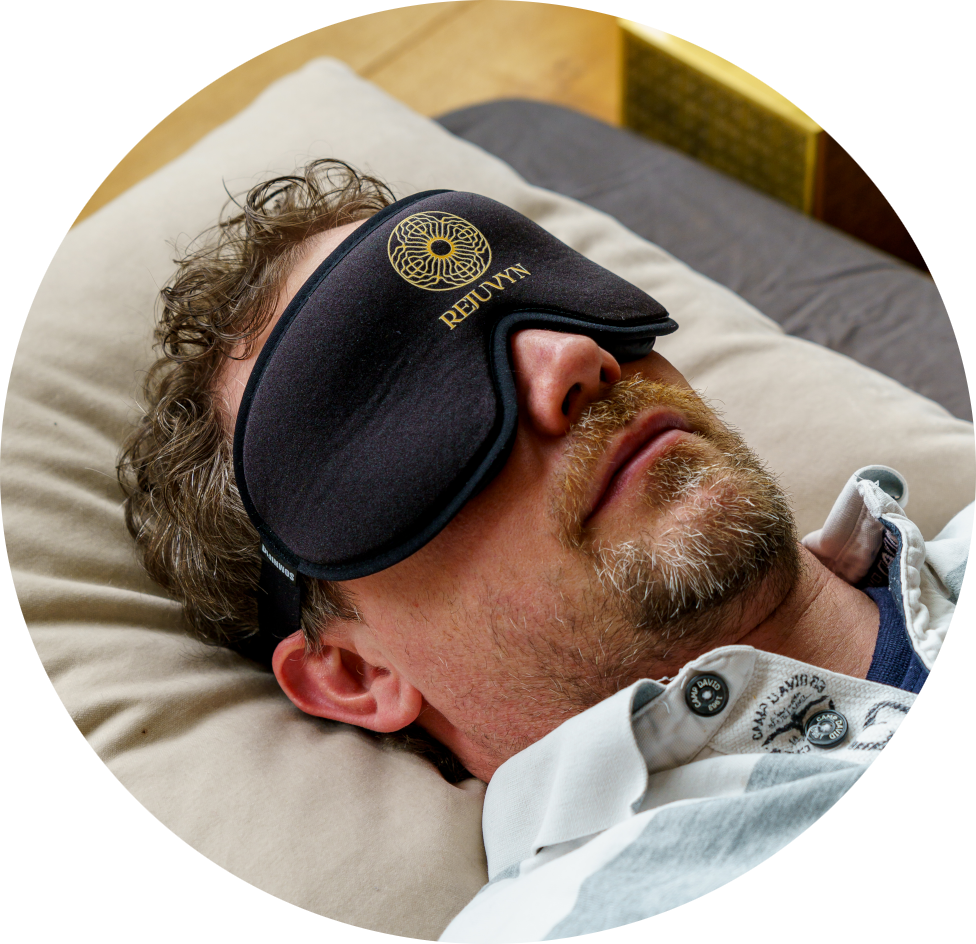Guy with black Rejuvyn blindfold laying on mattress