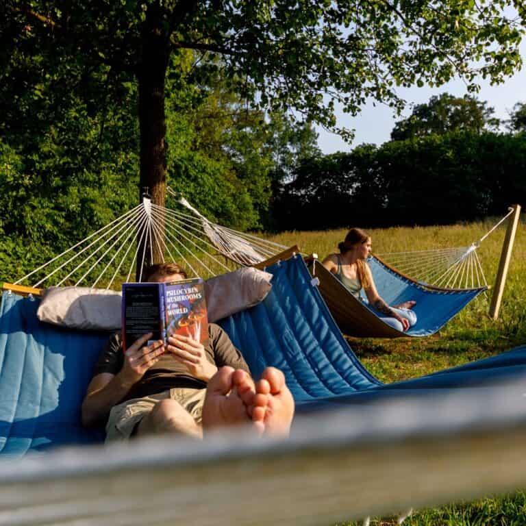 two people laying in two hammocks connected to a tree