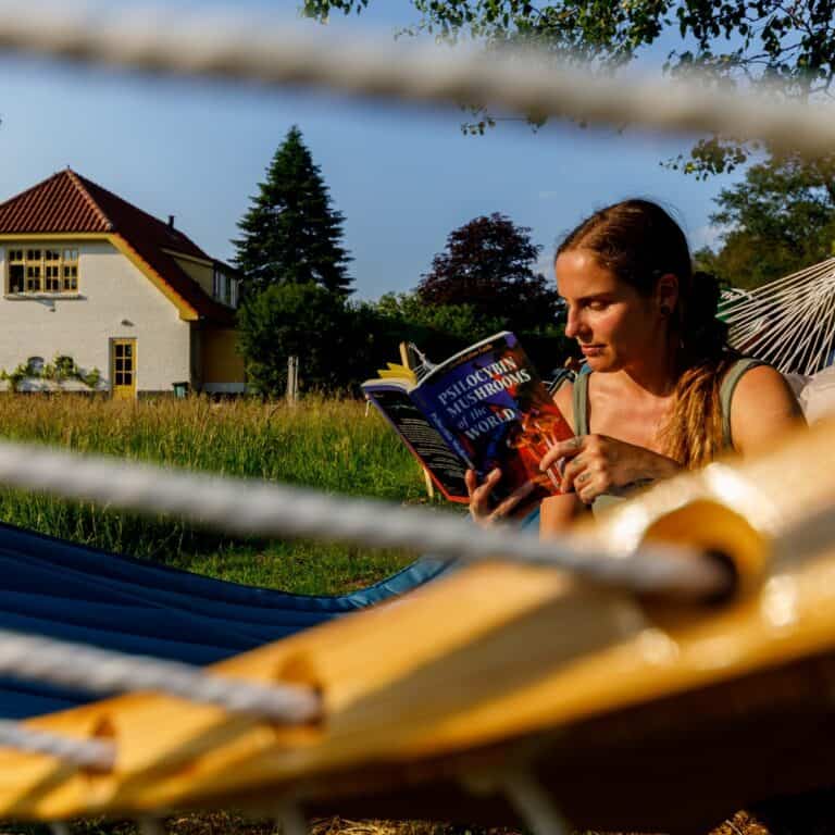 Woman sitting in hammock and reading a book