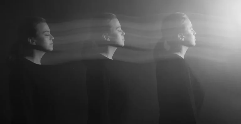 A black and white photo shows a woman in three overlapping positions, eyes closed, facing right. Blurred lines connect the figures, creating an effect of motion or transition. Light shines from the right side.