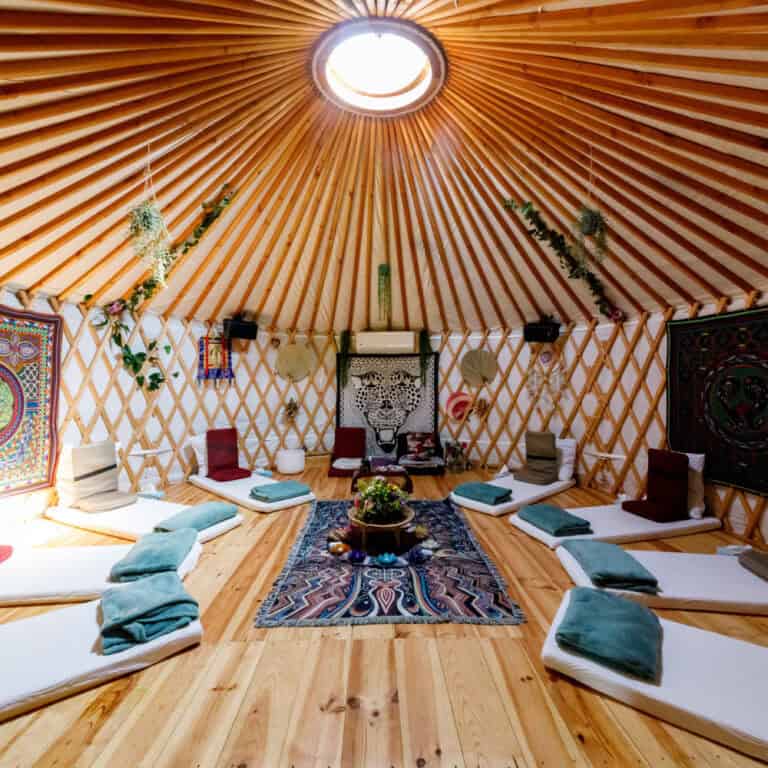 Yurt with mattresses, meditation seats, blankets and sun shining through sealing window