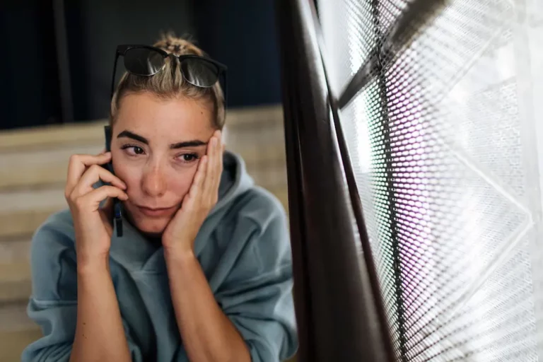 A girl in a blue hooded sweatshirt is having a sad phone conversation